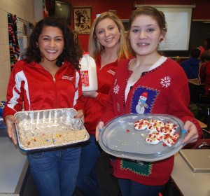 Sophomores Alexa Mahabeer(Left) and Sarah Relos(Right) share some of their homemade traditional food with the rest of their fellow students during a Spanish Celebration, while Sophomore Lexie Simpson(center) brings milk to top it all off.  