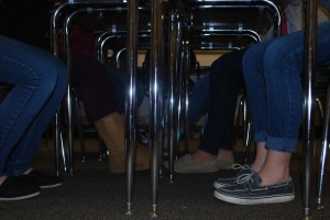 Students perch on the edge of their seats in a group formation. To the impercipient eye, this picture is not particularly intriguing, but if you observe closely, you will notice they are all wearing jeans. 