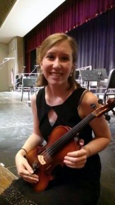 Korie is holding the violin she plays. Violin is just one of quite a few instruments she can play. 